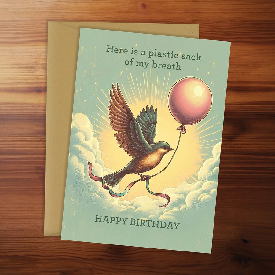 Birthday card with a bird and balloon design on a wooden surface