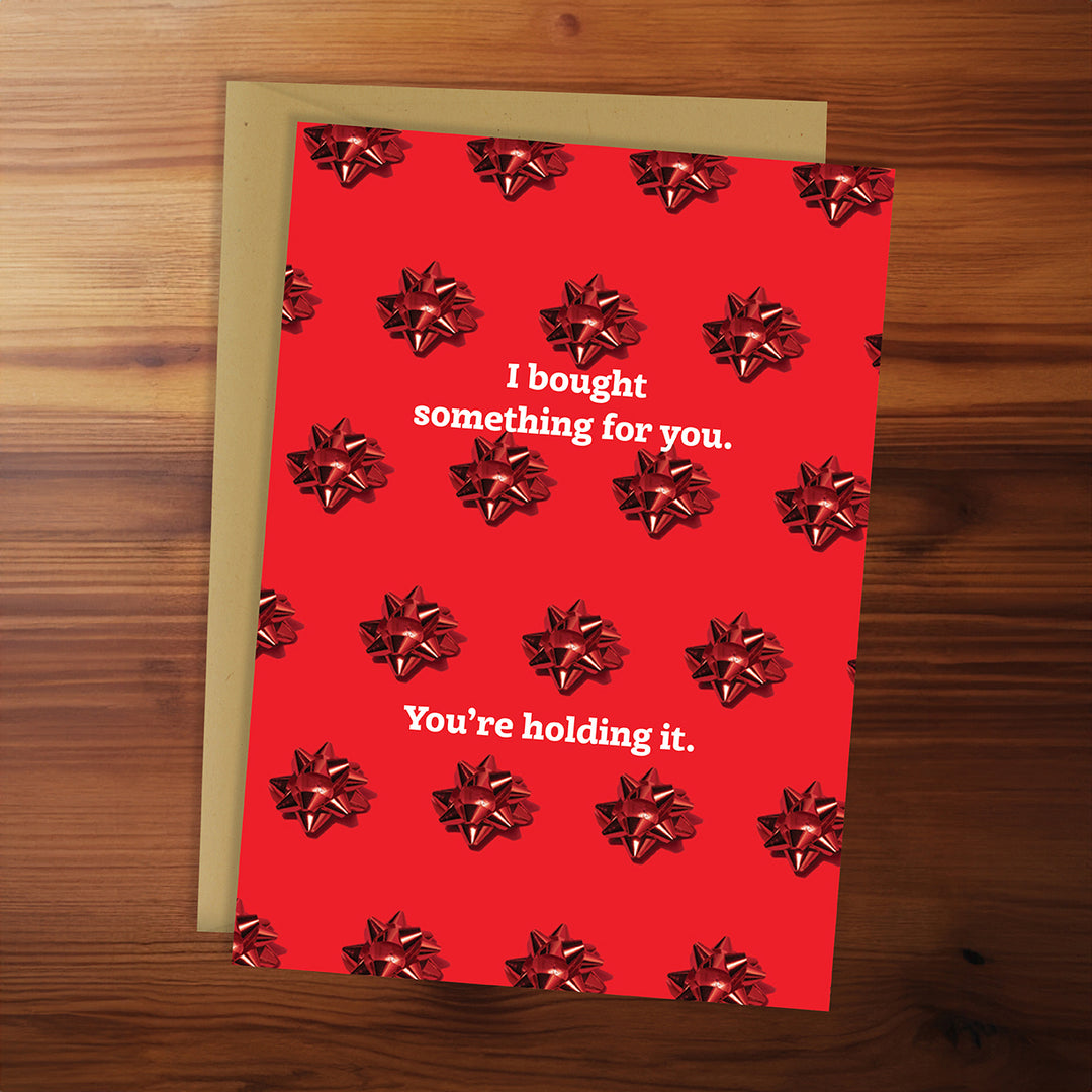 Red card with bow pattern and text on a wooden surface