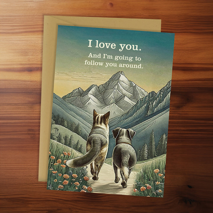 Greeting card with two animals walking together and a mountainous landscape, on a wooden surface.