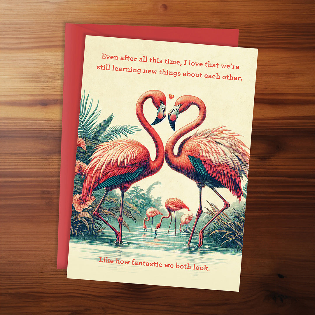 Greeting card with flamingo design and romantic text on a wooden surface