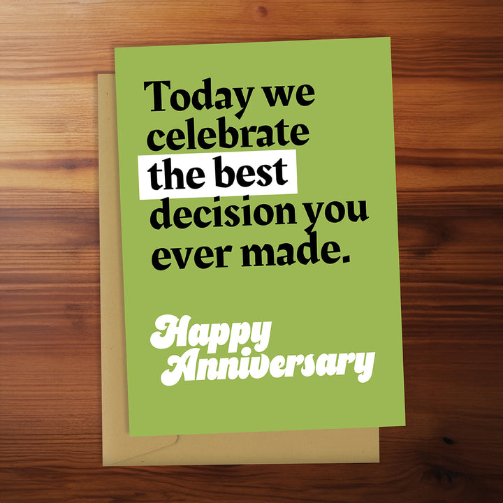 Green anniversary card with humorous message on a wooden surface