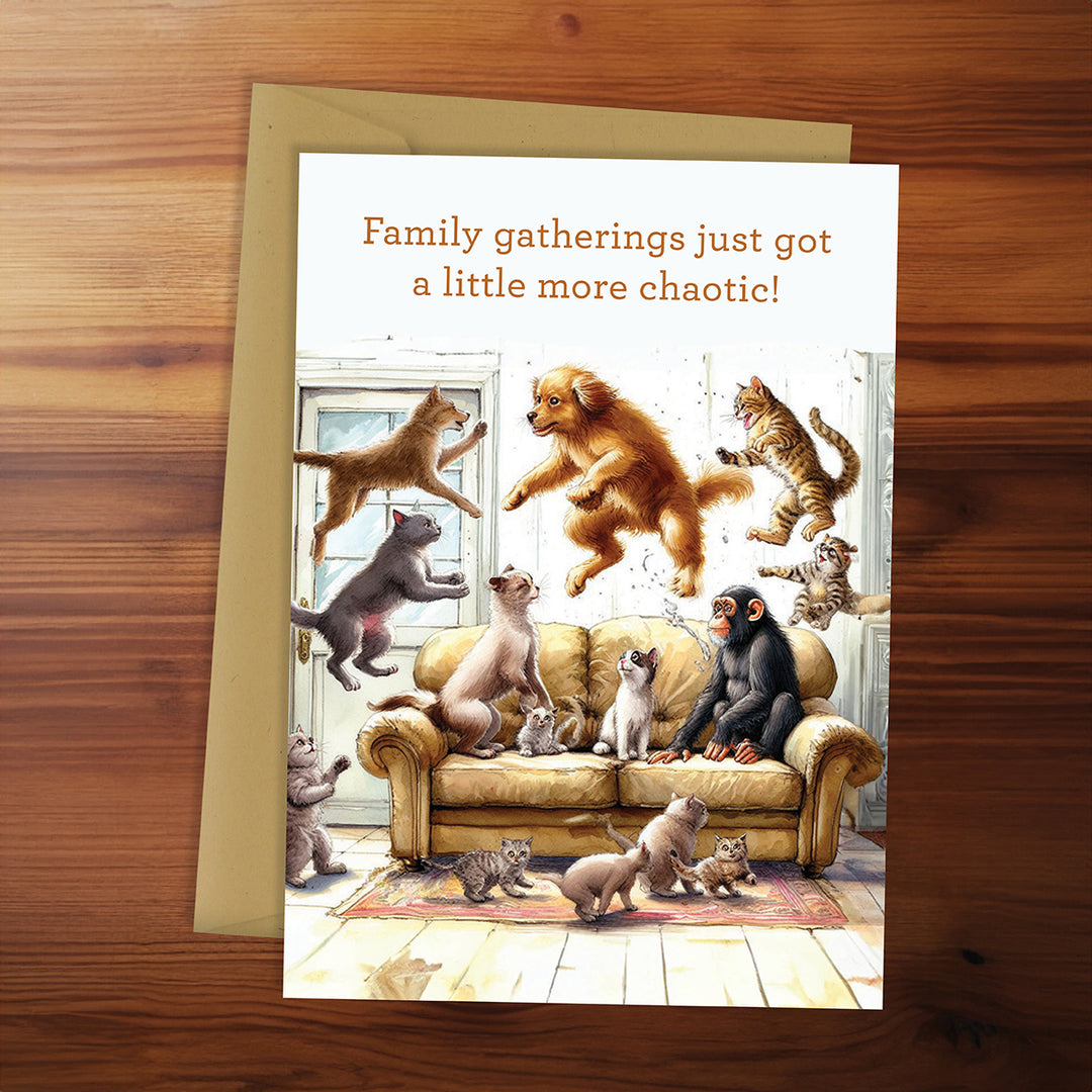 Card with illustration of animals on a couch and text 'Family gatherings just got a little more chaotic!' on a wooden surface.