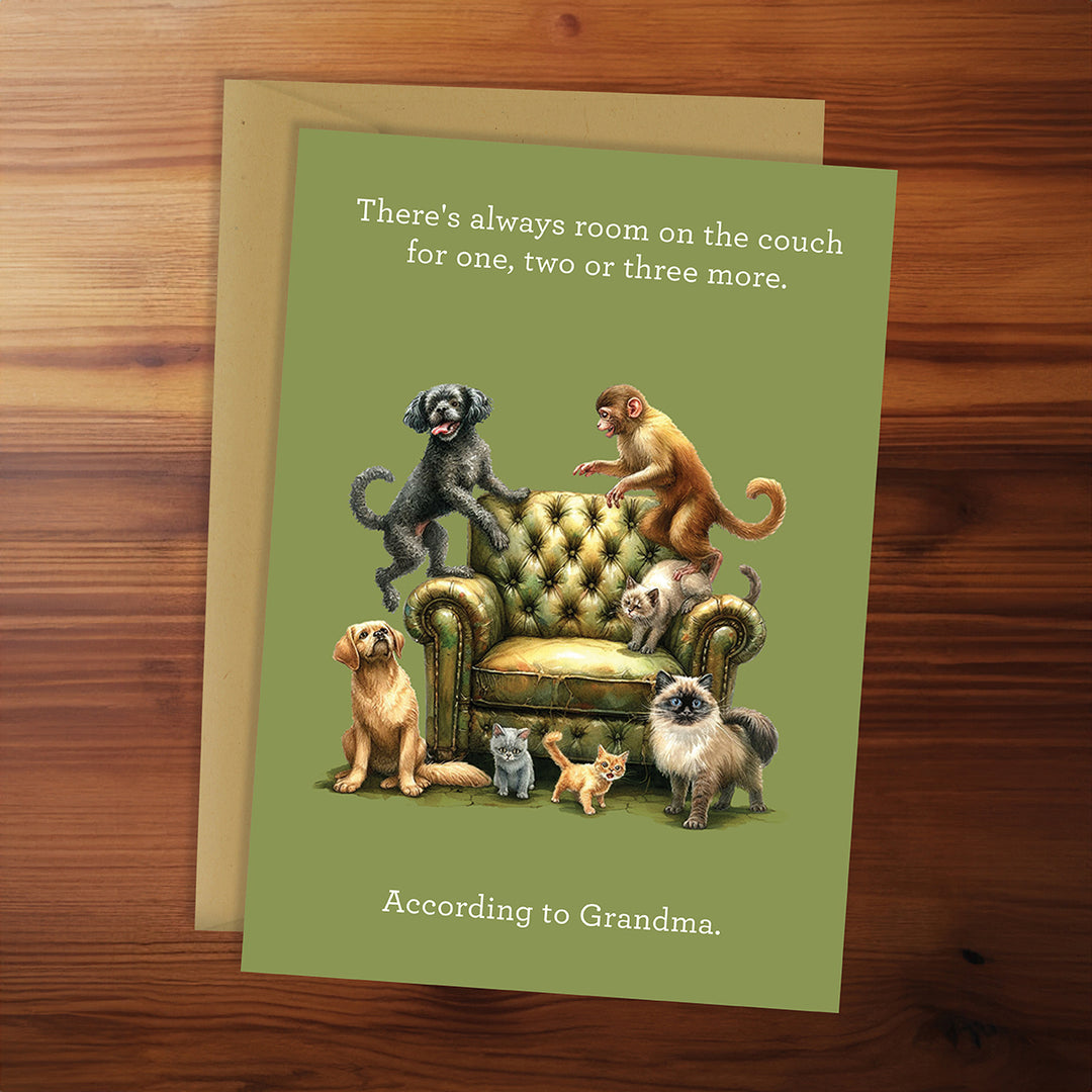 Card with animals on a couch and humorous text on a wooden surface