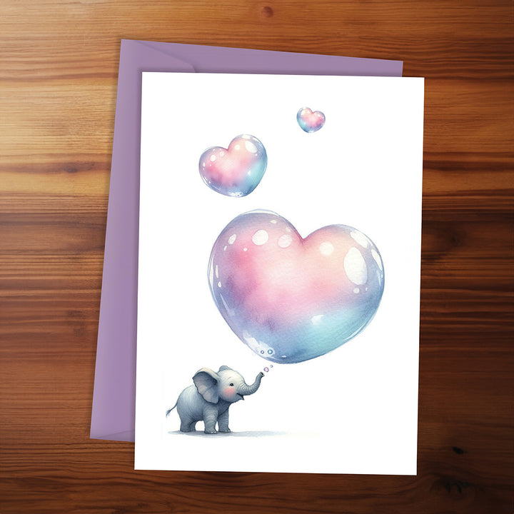 Card with a cartoon elephant holding a heart-shaped bubble on a wooden surface