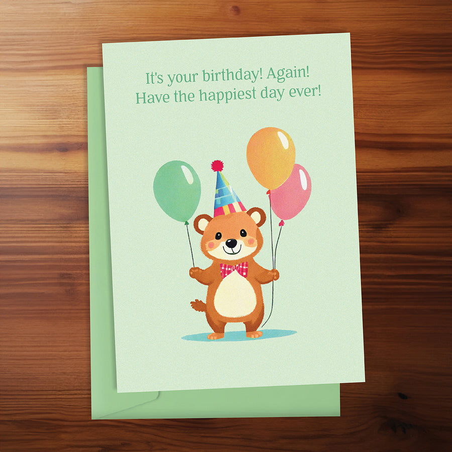 Birthday card with a bear holding balloons on a wooden surface