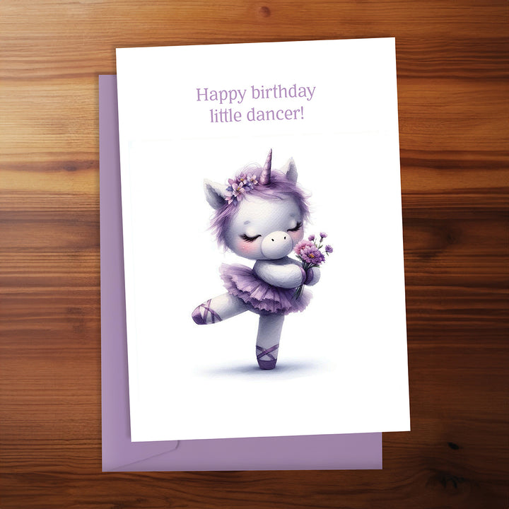 Greeting card with a unicorn dancer illustration on a wooden surface