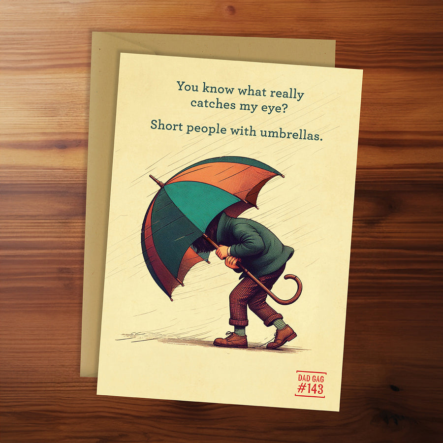 Greeting card with illustration of a person holding an umbrella and humorous text on a wooden surface