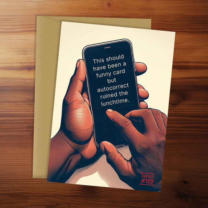 Greeting card with illustration of hands holding a phone and humorous text on a wooden surface