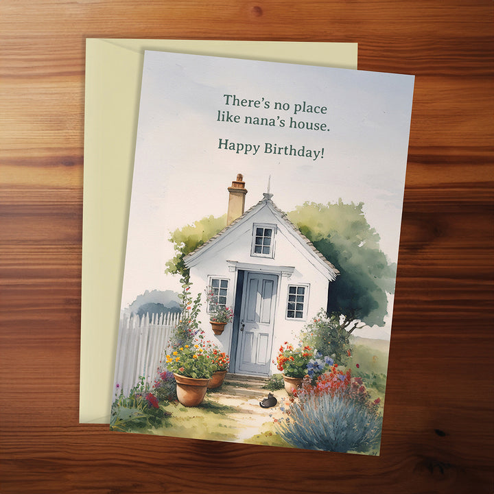 Birthday card with a house illustration and text on a wooden surface