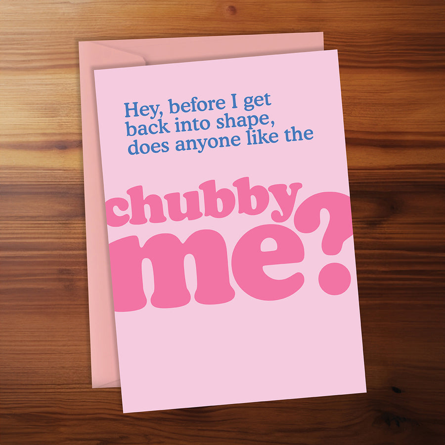 Pink card with humorous text on a wooden surface