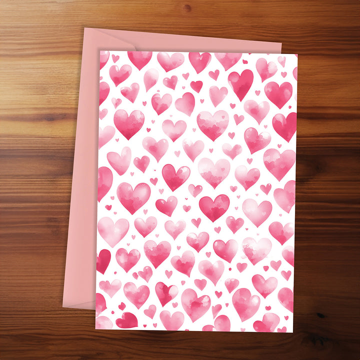 Greeting card with pink heart pattern on a wooden surface