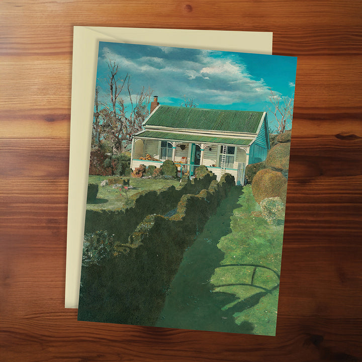Greeting card with a house and garden illustration on a wooden surface