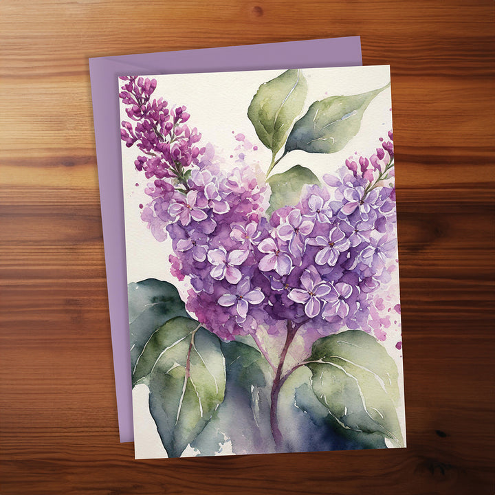 Greeting card with purple flowers and green leaves on a wooden surface