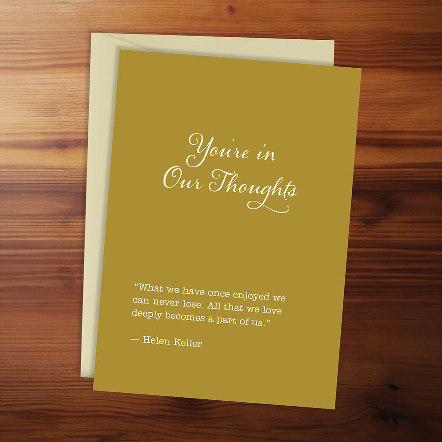 Greeting card with 'You're in Our Thoughts' message on a wooden surface