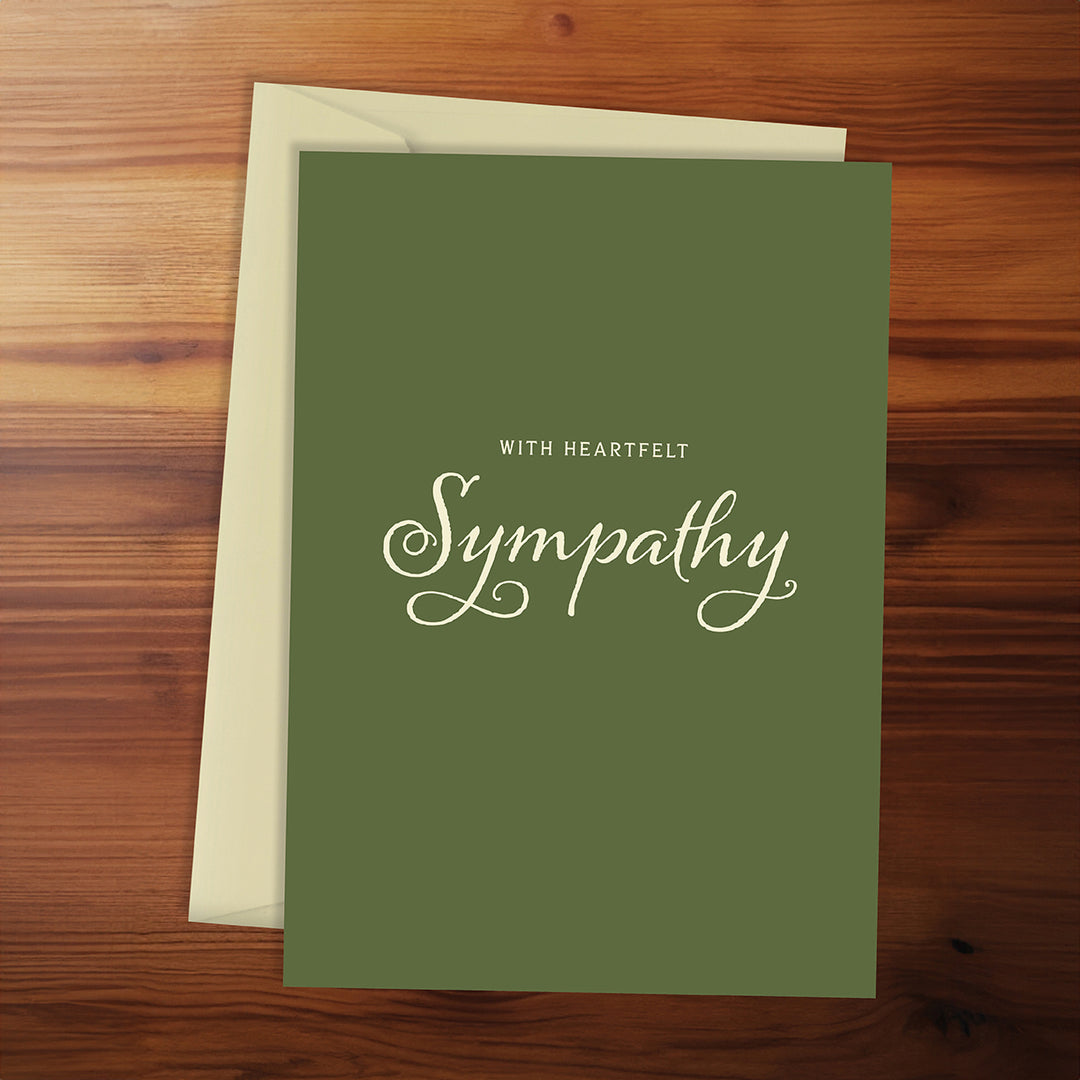 Sympathy card with 'With Heartfelt Sympathy' text on a wooden surface