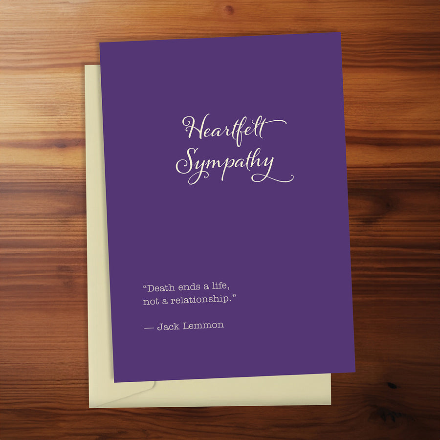 Purple sympathy card with white text on a wooden surface