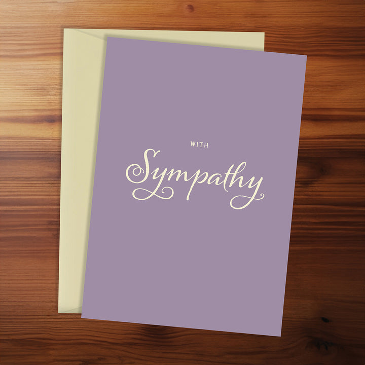 Purple card with 'With Sympathy' text on a wooden surface