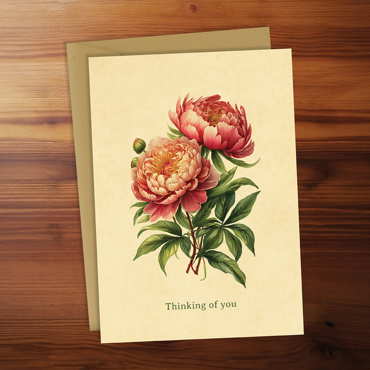 Greeting card with floral design and 'Thinking of you' text on a wooden surface