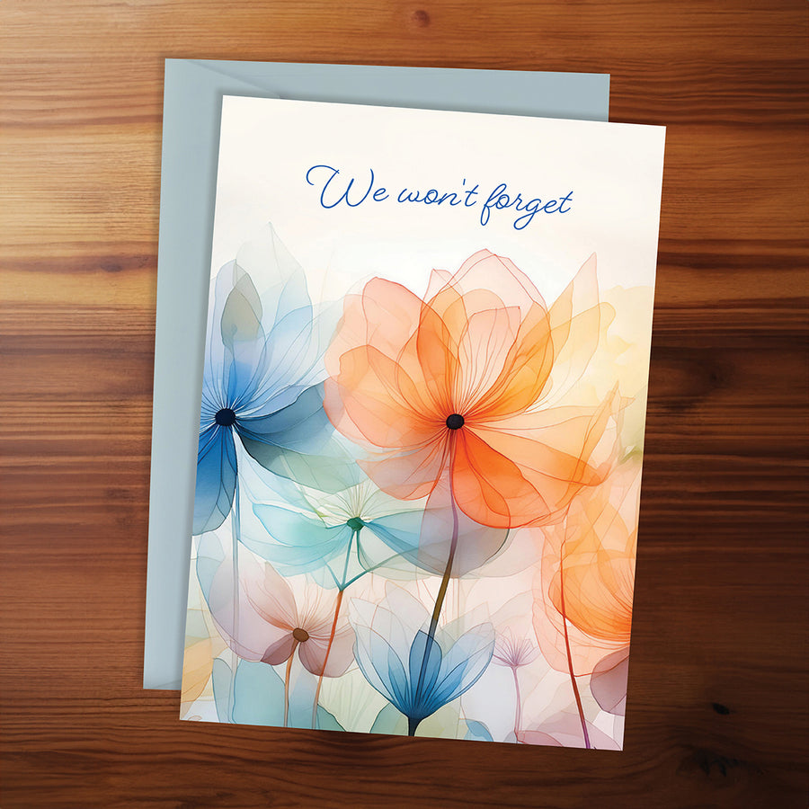 Greeting card with colorful floral design and 'We won't forget' text on a wooden surface
