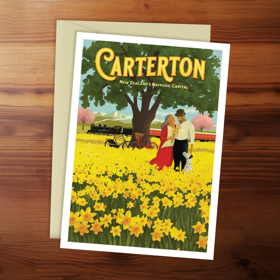 Poster of Carterton, New Zealand with a couple in a field of yellow flowers on a wooden surface.